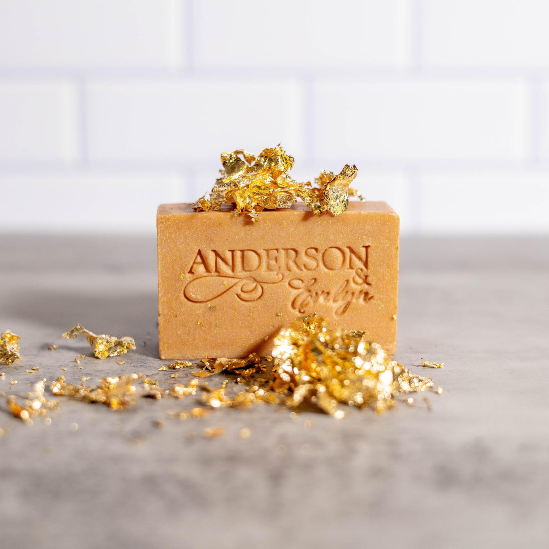 Natural copper-infused soap bar with gold leaf flakes on a gray surface, close-up.