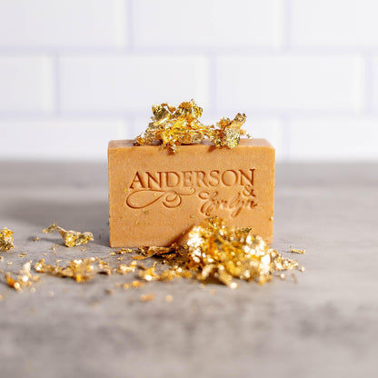 Natural soap bar with engraved text, decorated with gold leaf, on a gray countertop