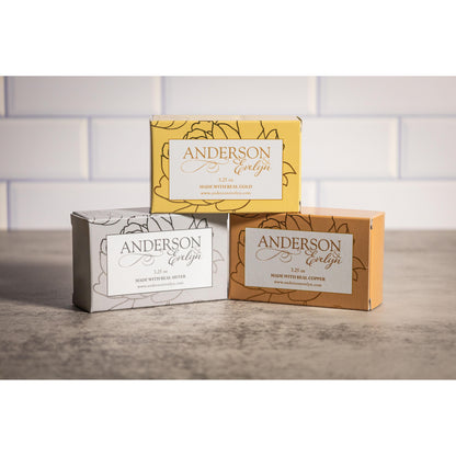 Three Andersonevelyn soap boxes with gold, silver, and copper labels on a countertop